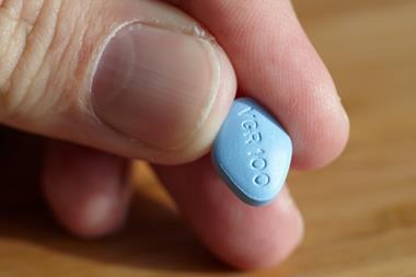 A hand holding a viagra tablet